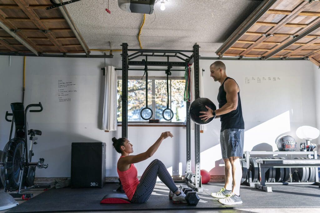 Woman exercising with personal trainer in home gym