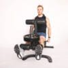 Powertec Workbench Leg Extension/Curl Attachment on workbench and two weight plates with Model doing leg extensions.