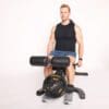Powertec Workbench Leg Extension/Curl Attachment on workbench and two weight plates with Model in ready position for leg extensions.
