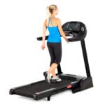 A woman walking on a treadmill, adjusting the settings on the console for a low-impact cardio workout.