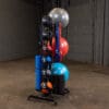 A gym storage rack holds stability balls, medicine balls, foam rollers, and mats for organized fitness equipment storage.