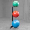 A vertical rack holds three stability balls in green, red, and blue, keeping them organized and accessible for workouts.