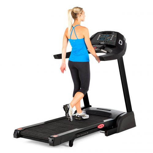 A woman walking on a treadmill, adjusting the settings on the console for a low-impact cardio workout.
